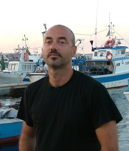 Lo scrittore Cosimo Argentina con lo sfondo di un'area portuale